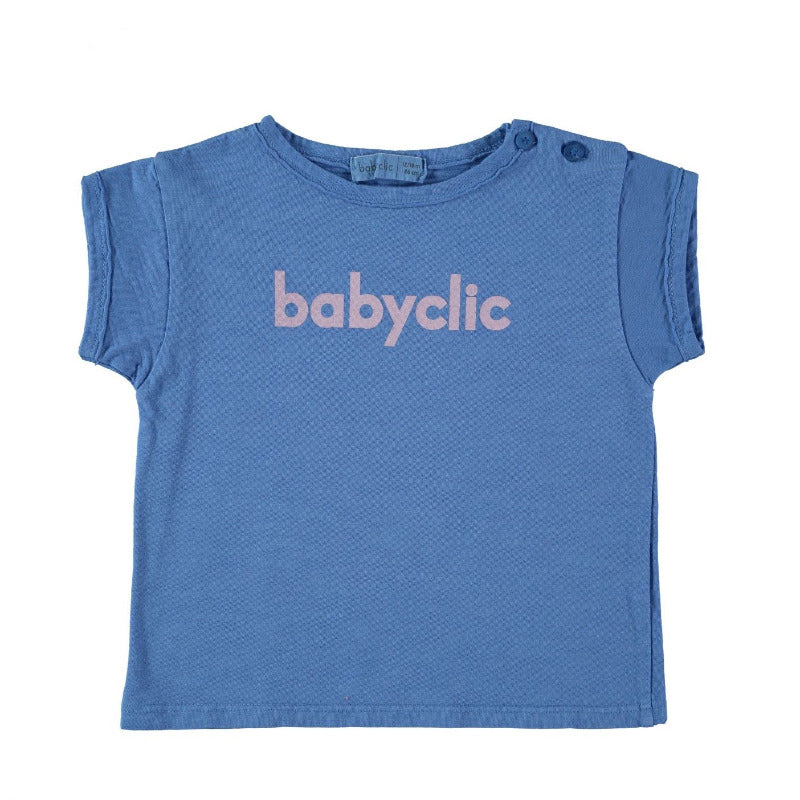 Una bellissima t-shirt per i vostri bambini in morbido e fresco cotone biologico a manica corta, con il logo babyclic su fondo blu elettrico. Apertura lungo spalla tramite bottoncini, finiture con bordi grezzi, tintura in capo.