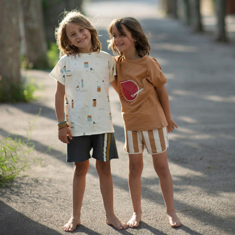 Una bellissima t-shirt per i vostri bambini in morbido e fresco cotone biologico a manica corta, con la stampa di una grande gazpacho su fondo caramello. Apertura lungo spalla tramite bottoncini.