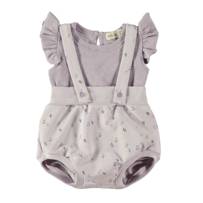 Bellissimo completo neonata con una salopette corta in cotone biologico in tonalità lavanda e una t-shirt a costine con dettagli a volants.