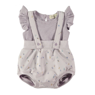 Bellissimo completo neonata con una salopette corta in cotone biologico in tonalità lavanda e una t-shirt a costine con dettagli a volants.