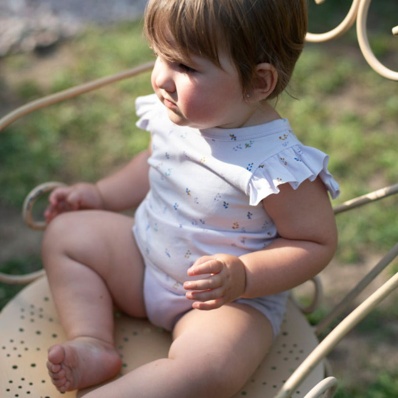 t-shirt bambina in cotone biologico, con tanti piccoli fiori su tonalità lavanda. Volants sulle spalle, apertura tramite bottone ad altezza collo nella parte posteriore