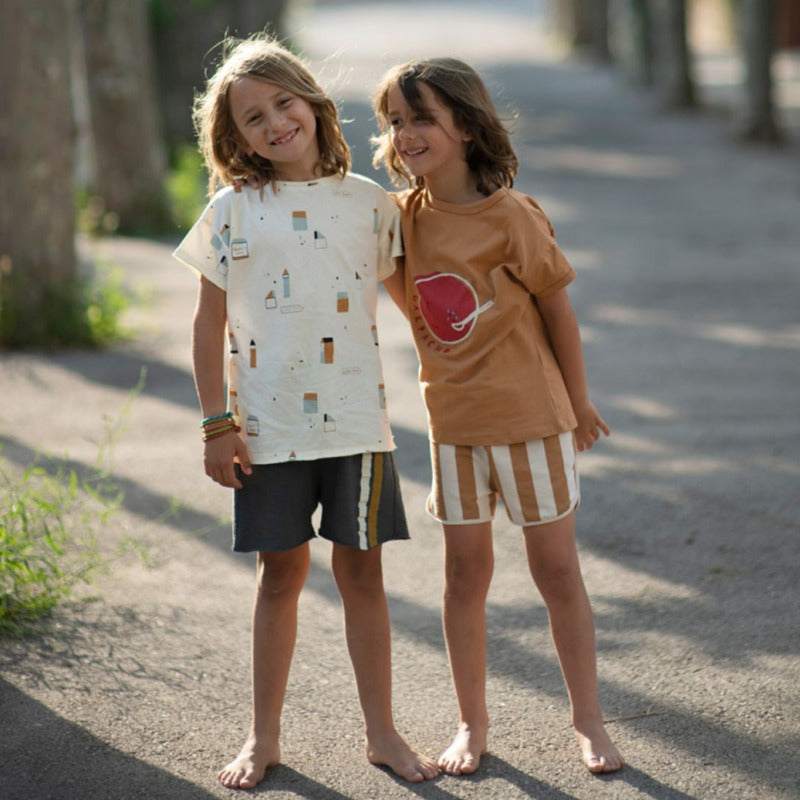 Bellissimo bermuda per i vostri bambini in cotone biologico con trama a righe caramello e panna. Elastico in vita, chiusura a cordoncino, profili cordati.