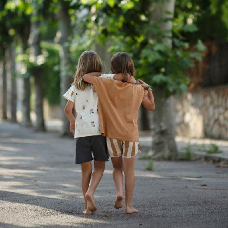 Bellissimo bermuda per i vostri bambini in cotone biologico con trama a righe caramello e panna. Elastico in vita, chiusura a cordoncino, profili cordati.