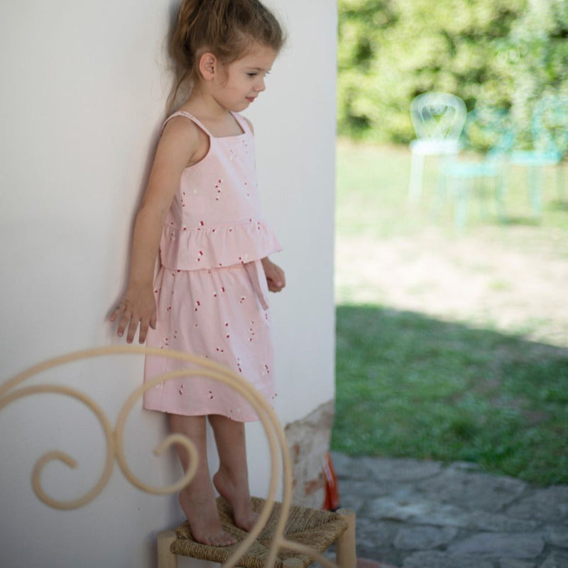 Un grazioso top per la vostra bambina in cotone biologico, con tanti piccoli petali su tonalità rosa. Apertura posteriore tramite bottoni, volants sula parte inferiore del top.