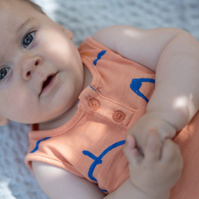 Grazioso pagliaccetto per i vostri bambini in morbido cotone biologico con tanti frutti su fondo arancio. Chiusura frontale con bottoni, elastico sui polsini, apertura inguinale tramite bottoncini a pressione.