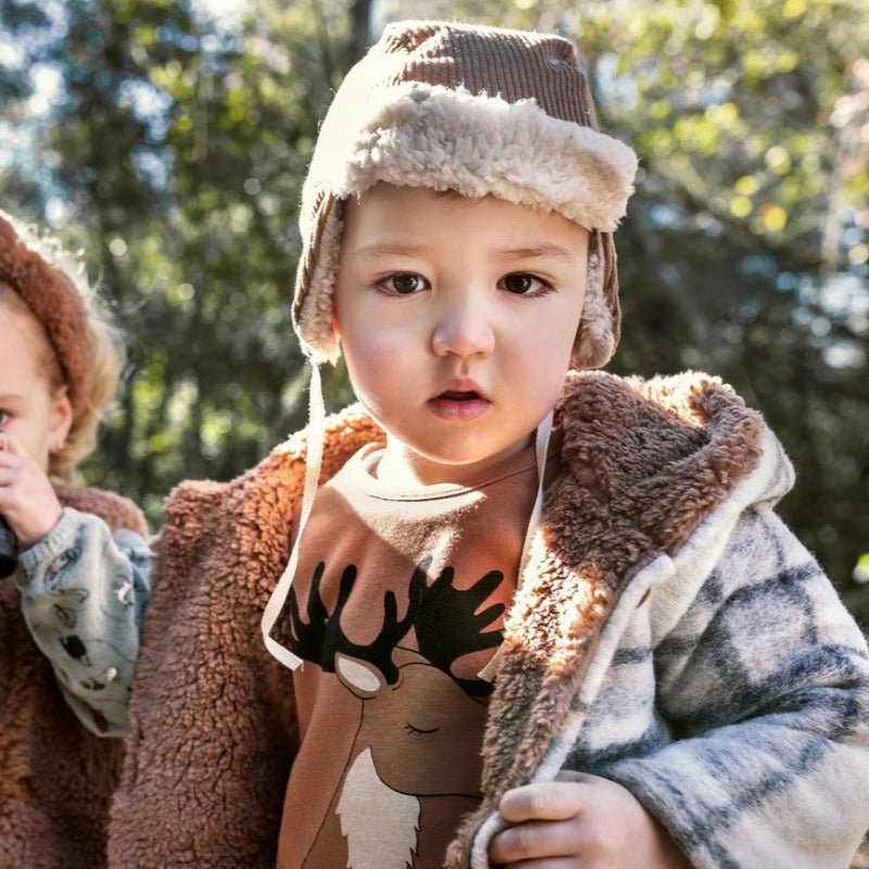 Un bellissimo cappotto in lana, perfetto per tenere al caldo il corpo dei vostri bambini. Questa giacca è fornita di cappuccio e ha un'apertura frontale tramite bottoni in bio resina. L'interno è in morbida fodera di eco pelliccia.